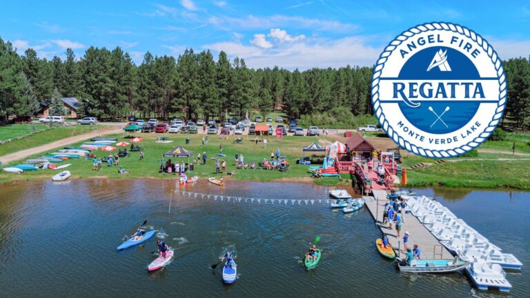 Regatta - Visit Angel Fire New Mexico Aerial view of a lakeside regatta event with people on the lawn, boats and jet skis on the water, tents and cars along the shore, and a large circular Regatta emblem in the top-right corner.