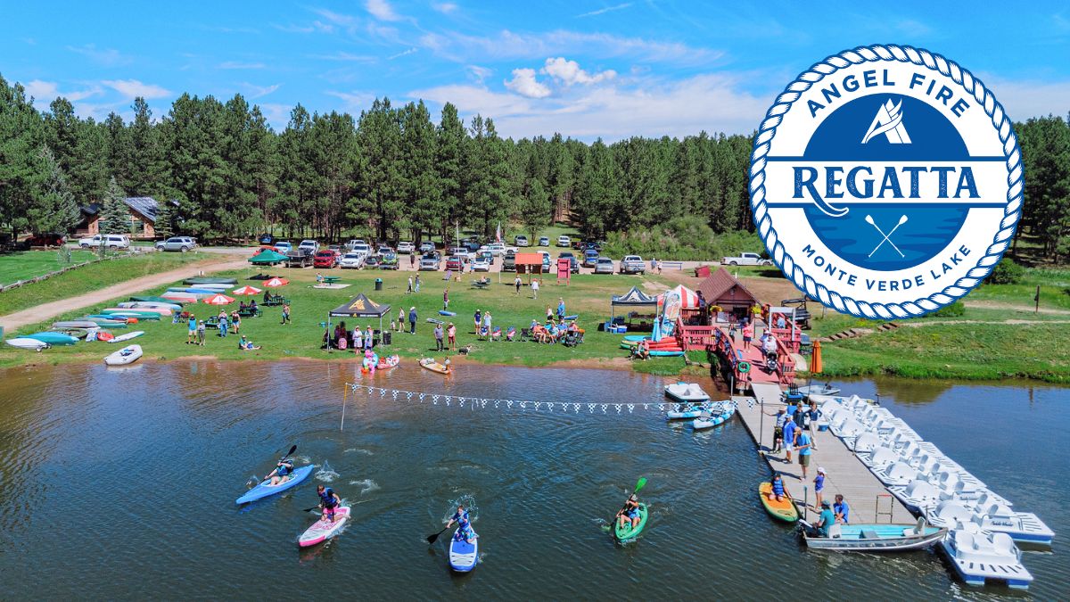 Regatta - Visit Angel Fire New Mexico Aerial view of a lakeside regatta event with people on the lawn, boats and jet skis on the water, tents and cars along the shore, and a large circular Regatta emblem in the top-right corner.